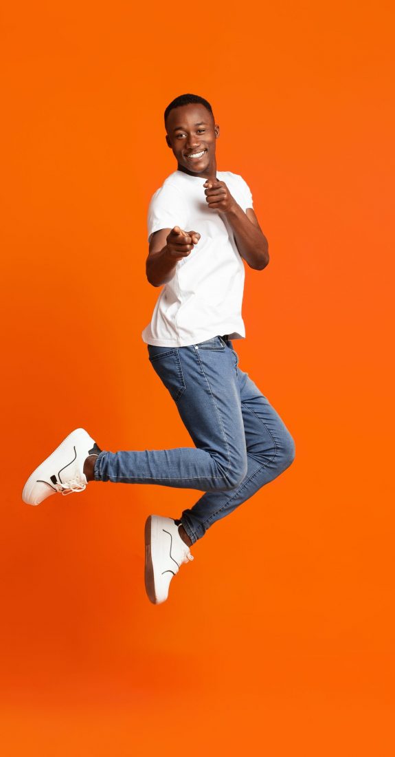 Charismatic,Black,Guy,Pointing,At,Camera,While,Jumping,Up,On